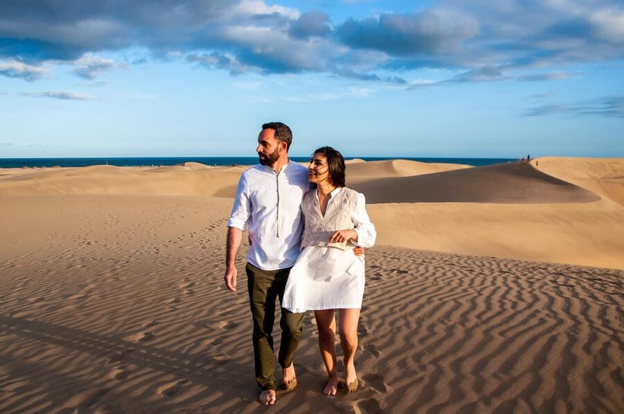 Two walkers crossing the Maspalomas dunes with the Atlantic behind them